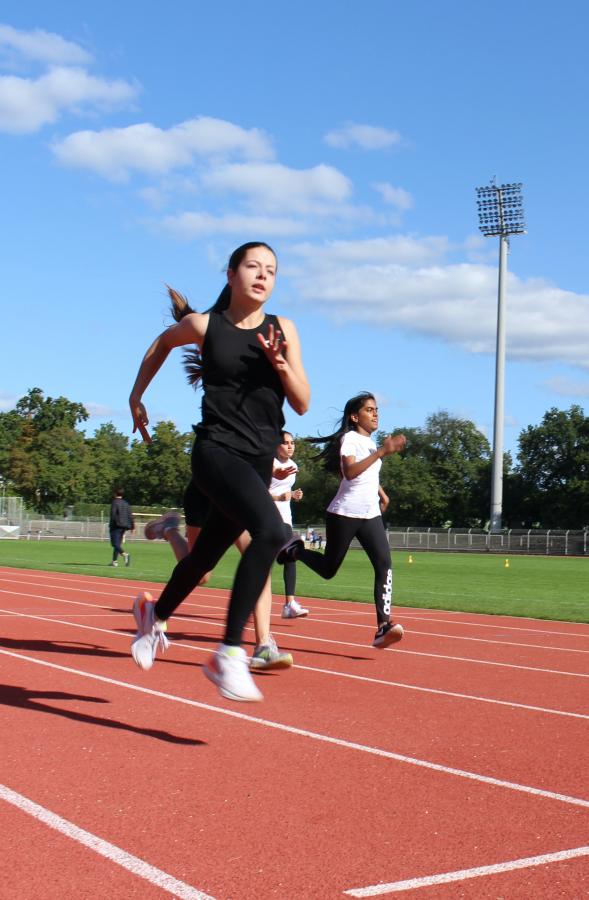 Mädchen sprinten auf einer Rennbahn in einem Sportstadion. 