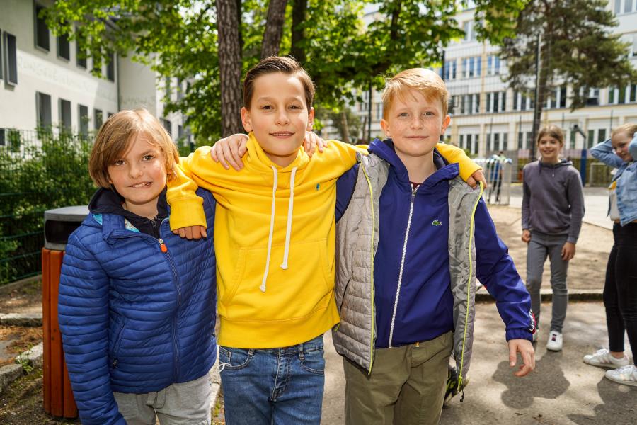 Drei jungen stehen Arm in Arm auf dem Schulhof. 